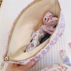 Detail of pink jacquard makeup bag interior with heart patterns and lucky ribbon