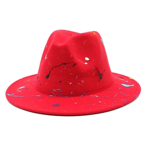 Artistic red fedora hat featuring colorful paint splatter graffiti and a wide brim style