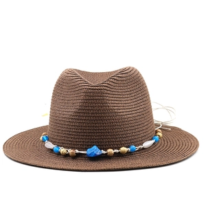 Detail of hand-woven brown straw sun hat with ethnic style beaded band decoration