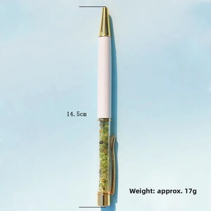 Detail of elegant white ballpoint pen featuring green crystal stones and gold accents
