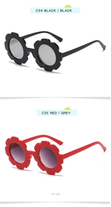Detail view of flower-shaped kids sunglasses in black and red frames with gray lenses