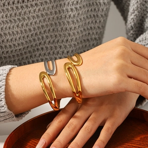 Close-up of minimalist gold and silver stainless steel open bracelets layered on a wrist