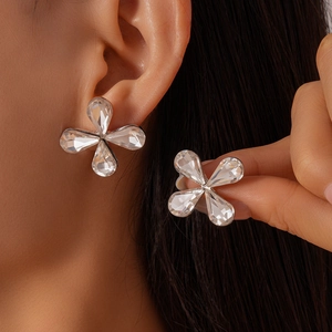 Detailed view of glass flower stud earrings featuring teardrop crystals on model