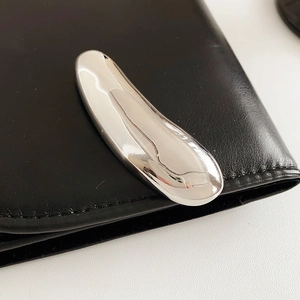 Close-up of minimalist silver metallic buckle on premium black leather material