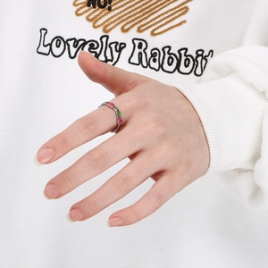 Close-up of colorful heart enamel silver rings worn on a hand against white fabric