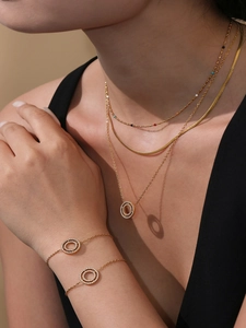 Detailed view of model wearing gold layered necklaces and bracelets with cubic zirconia rings