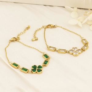 Detail of clover gemstone bracelets with green and white crystals on white silk