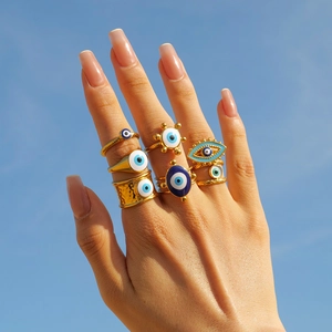 Close-up of a stacked set of gold evil eye rings with blue enamel on a hand