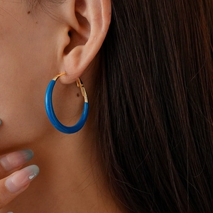 Close-up of minimalist klein blue enamel hoop earring worn by a model in profile