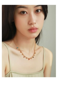 Close-up of gold beaded necklace with colorful enamel charms worn by a model