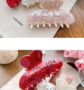Détail macro de pinces à cheveux coeur en strass aux finitions nacrées rose, rouge et blanc