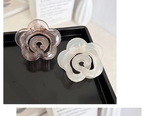 Close-up of elegant amber and matte white flower hair claws on a sleek black display tray
