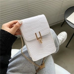 Detail of white crocodile pattern leather phone bag with golden U-shaped metal clasp