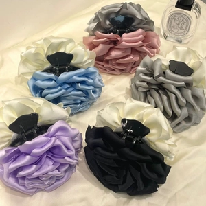 Detailed close-up of six satin flower hair claws in assorted pastel colors on soft fabric