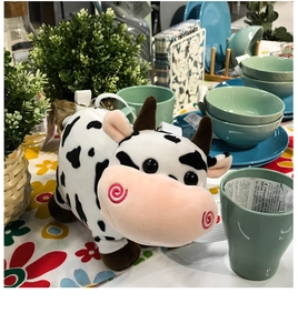 Close-up of cute black and white plush cow toy with pink snout on a decorated table