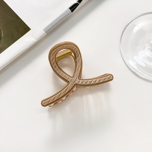 Detailed view of beige twisted claw clip with visible metal spring on white background
