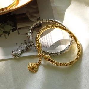 Macro detail of gold and silver twisted bangles featuring elegant shell charms