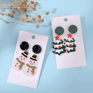 Detail of Christmas snowman and tree acrylic earrings on a white display card