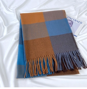 Close-up of checked scarf texture with orange and blue fringe on satin background