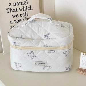 Top view of white quilted rabbit print makeup bag with handle and zipper closure