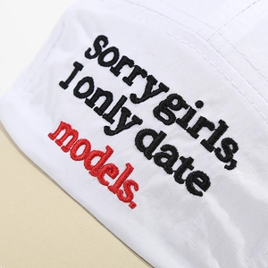 Detailed close-up of premium white twill cotton baseball cap with intricate text embroidery