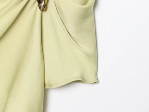 Detail of light green satin top featuring pleated texture and unique gold metal buckle