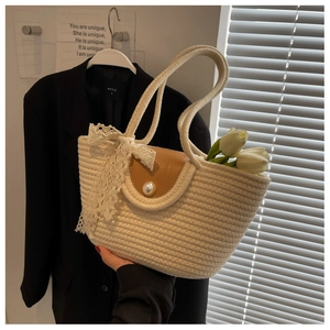 Detail of cream woven tote bag featuring a pearl button closure and white lace bow