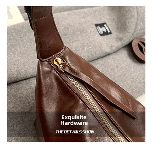 Detail of high-quality golden metal zipper and dark brown glossy leather shoulder bag