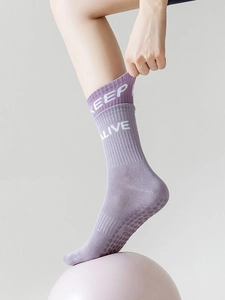 Close-up of purple yoga socks with KEEP ALIVE text and anti-slip silicone dots on a ball