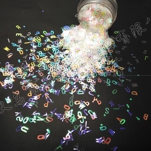 Macro shot of 3mm rainbow laser alphabet sequins for nail art and DIY crafts