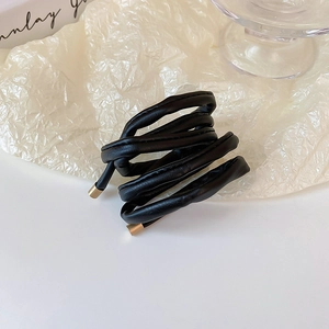 Detailed macro of black faux leather hair tie with elegant gold metal finish on ends