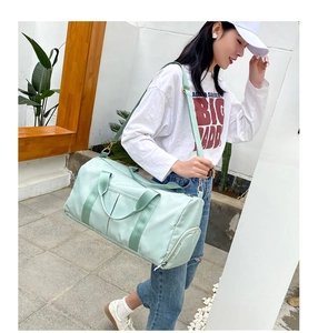 Woman carrying mint green large fitness travel bag with shoulder strap in outdoor setting