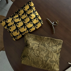 Detailed texture of elephant jacquard cosmetic bag and olive green floral embroidery pouch