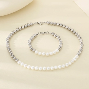 Parure de bijoux en perles argentées et blanches avec collier et bracelet sur tissu