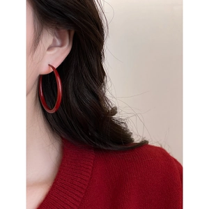 Side view of a female model wearing large vintage-style red round hoop earrings