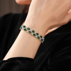 Nahaufnahme des zweilagigen Zirkonia-Armbands mit grünen Steinen am Handgelenk der Frau