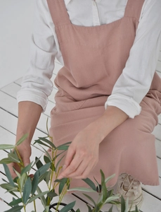 Detail of pink linen apron worn by a person gardening on a white wooden floor