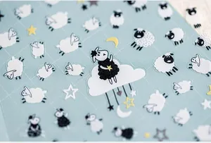 Close-up of 5D cartoon sheep nail stickers with clouds and stars on grid background