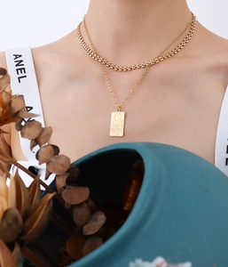 Gros plan d'un collier doré double épaisseur avec pendentif tarot sur un mannequin élégant