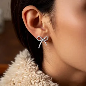Elegant silver bow ear cuff with pavé zircons worn by a model in warm lighting
