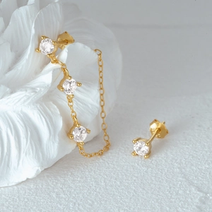 Detailed close-up of gold s925 silver stud earrings with zircon stones and chain link