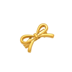 Macro detail of high-quality gold bow brooch with smooth metallic finish and elegant knot