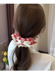 Detail of red checkered scrunchie with lace edge and brown bear charm on a bun hairstyle