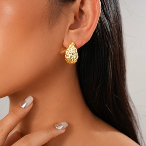 Gros plan de boucles d'oreilles dorées en forme de larme avec texture de métal martelé