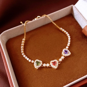 Detail von 18 Karat vergoldetem Armband mit bunten Herzanhängern und Zirkonia-Steinen