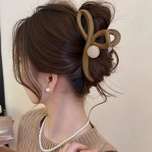 Detailed side view of brown bow hair claw clip with marble beads on elegant hairstyle