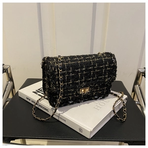 Detailed close-up of black and gold tweed shoulder bag with chain strap and metal lock