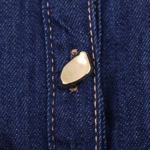Gros plan détaillé des boutons métalliques dorés sur la texture du tissu denim bleu