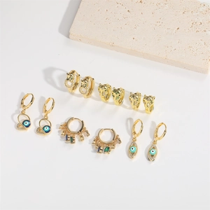 Détail de boucles d'oreilles dorées avec œil maléfique et tête de léopard en zircons