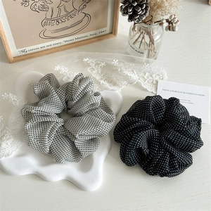 Flat lay of mesh polka dot scrunchies in gray and black colors on a minimalist desk